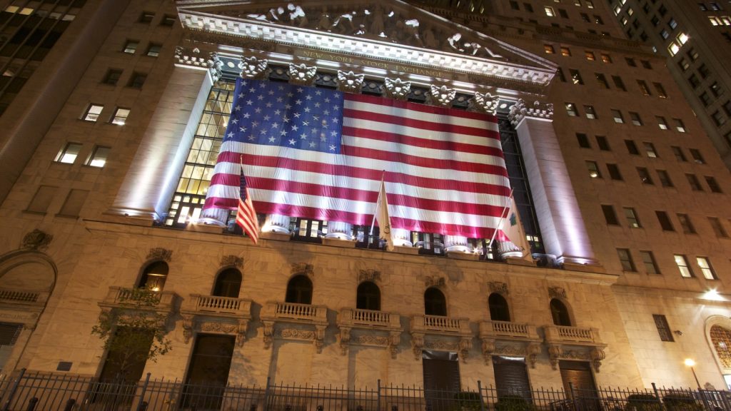 New York Stock Exchange facade with American flag at night, Wall Street financial district